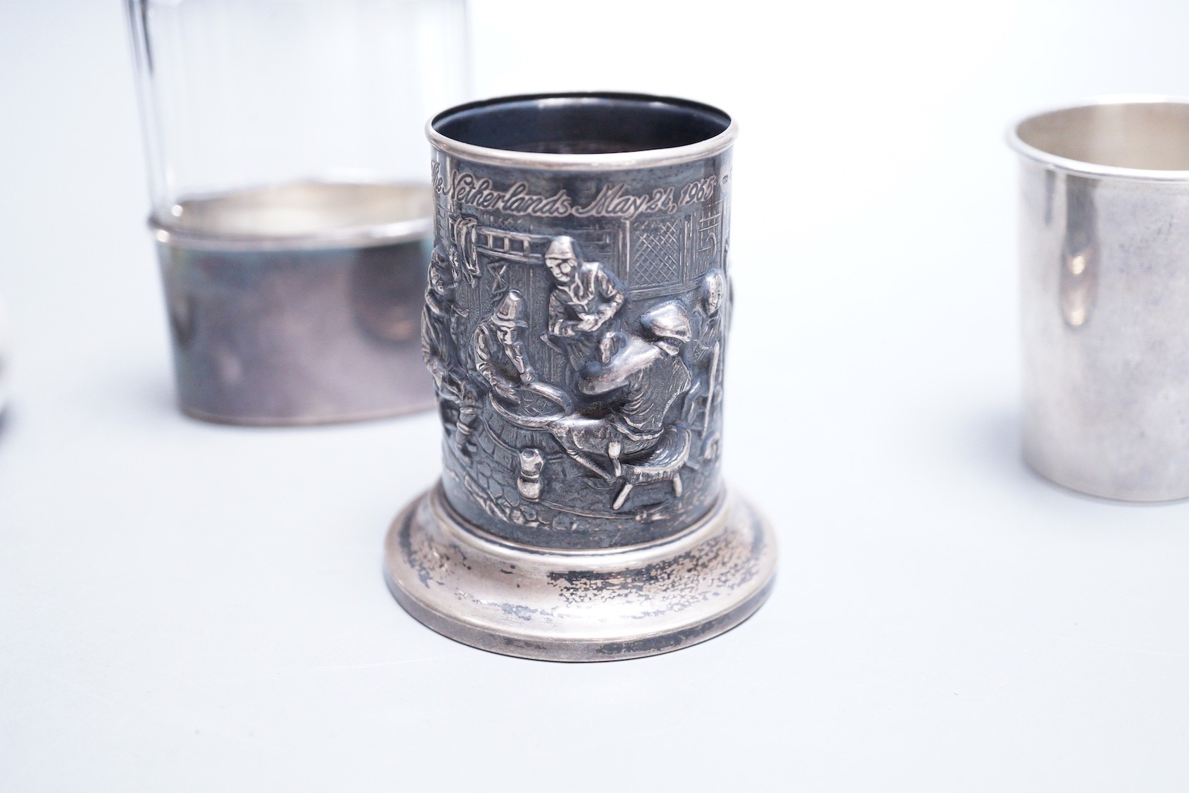 A Dutch embossed white metal cylindrical vase, 75mm, a French white metal small bachelor's hot water pot, an Italian 925 small beaker and a silver capped hip flask with plated cup.